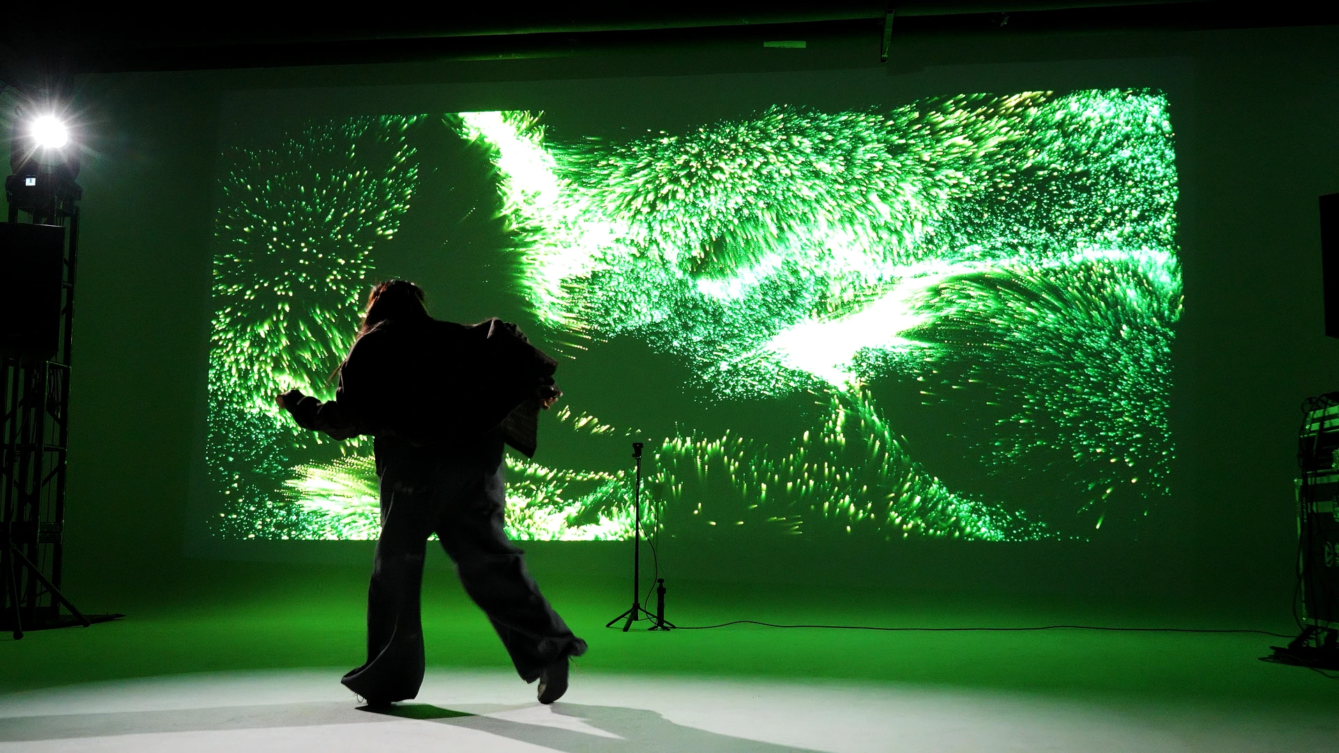 Dancer in front of a green particle projection